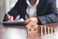 coins stacked next to model of house