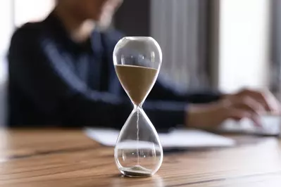 hourglass on desk while person works in background