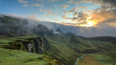Empty paved road winding through a misty green mountain valley at sunrise, with no people, vehicles, logos, or readable text.