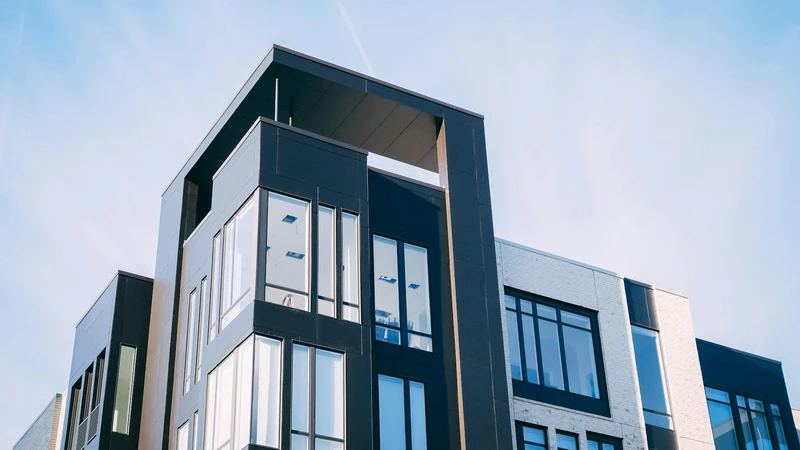 Modern multi-story condominium building with brick, glass, and dark panels against a clear sky, with no people, logos, or readable text.