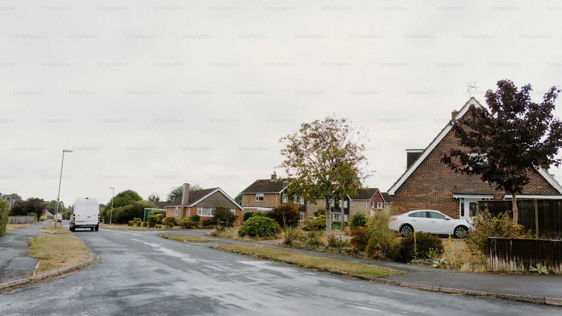 Quiet suburban street under an overcast sky with parked cars and no people, logos, or readable text.