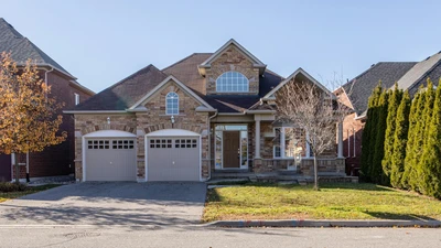 Stone and brick two-story house with a double garage and bare trees in late autumn light, no people or text