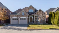 Stone and brick two-story house with a double garage and bare trees in late autumn light, no people or text