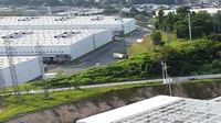 Industrial park buildings and loading areas under a clear sky with empty lots in the foreground, no people or text