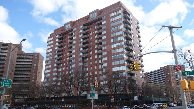 Mid-rise and high-rise residential buildings along a city street under a partly cloudy sky