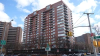 Mid-rise and high-rise residential buildings along a city street under a partly cloudy sky